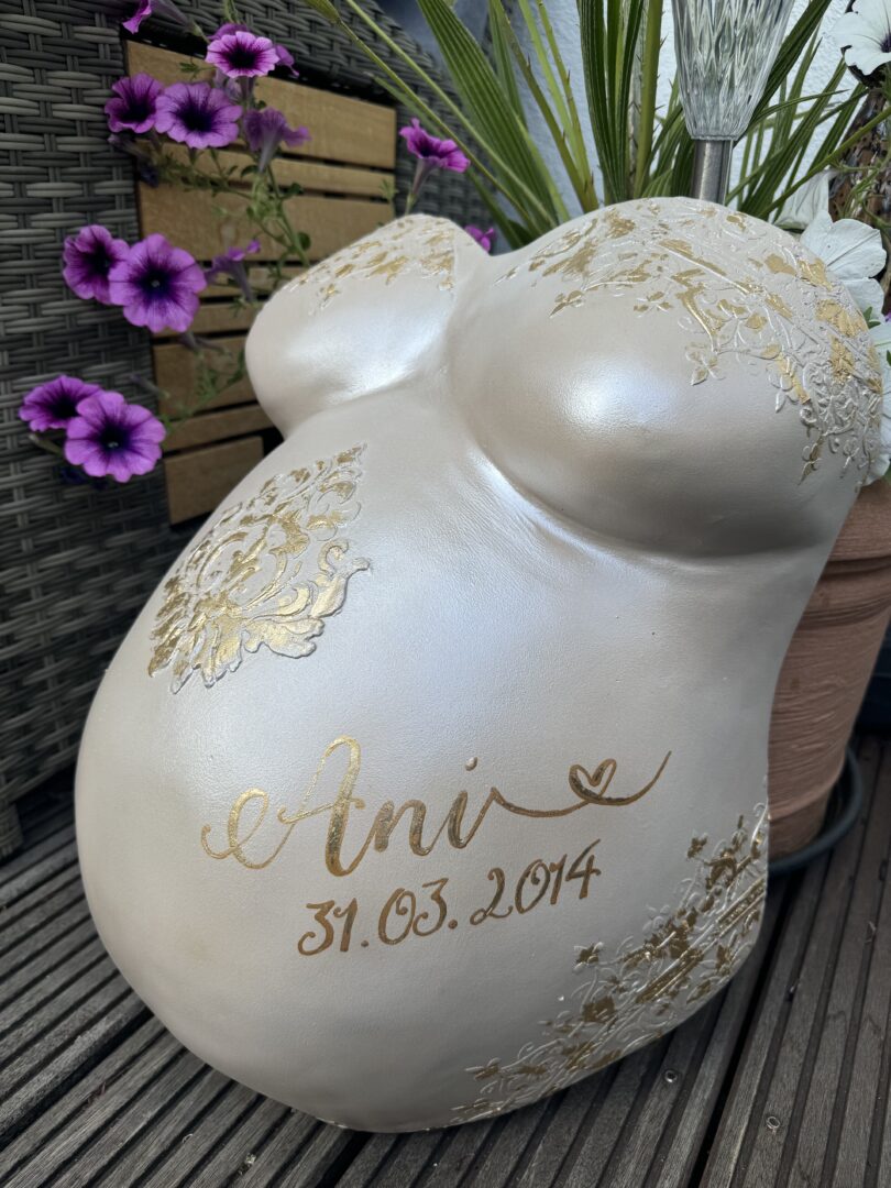 Babybauch-Gipsabdruck mit filigranen Verzierungen und Blattgold
