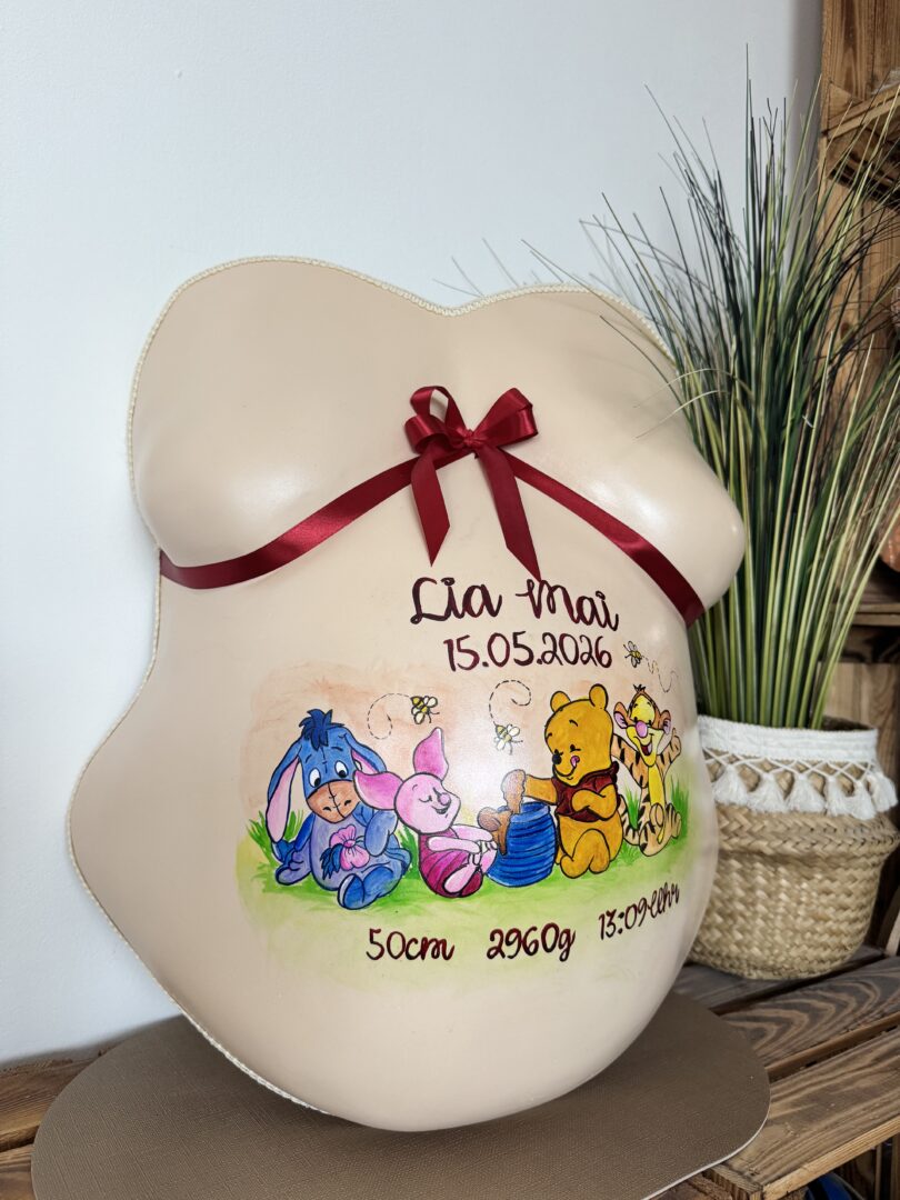 Hautfarbener Babybauch Gipsabdruck mit roter Schleife, handgemaltem Kinderfiguren-Motiv und persönlichen Geburtsdaten