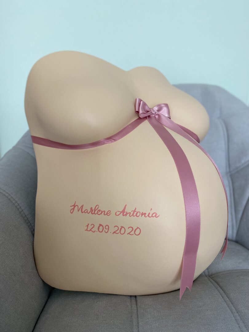 Puristischer hautfarbener Babybauch Gipsabdruck mit rosa Schleife und Geburtsdaten
