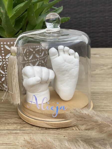 Gipsabdruck einer Babyhand und eines Babyfußes unter einer Glasglocke auf einem Holzsockel