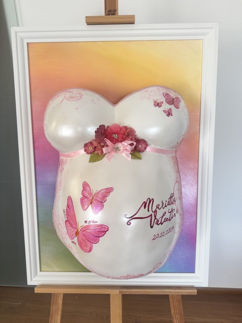 Babybauch-Gipsabdruck mit rosa Schmetterlingen und floraler Veredelung