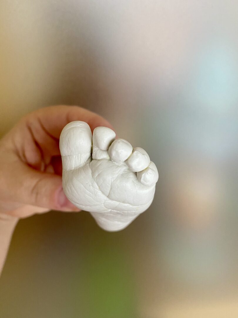 Detailaufnahme eines kleinen Babyfußes als detailgetreue Gipsabformung mit sichtbaren Zehen und feinen Hautlinien