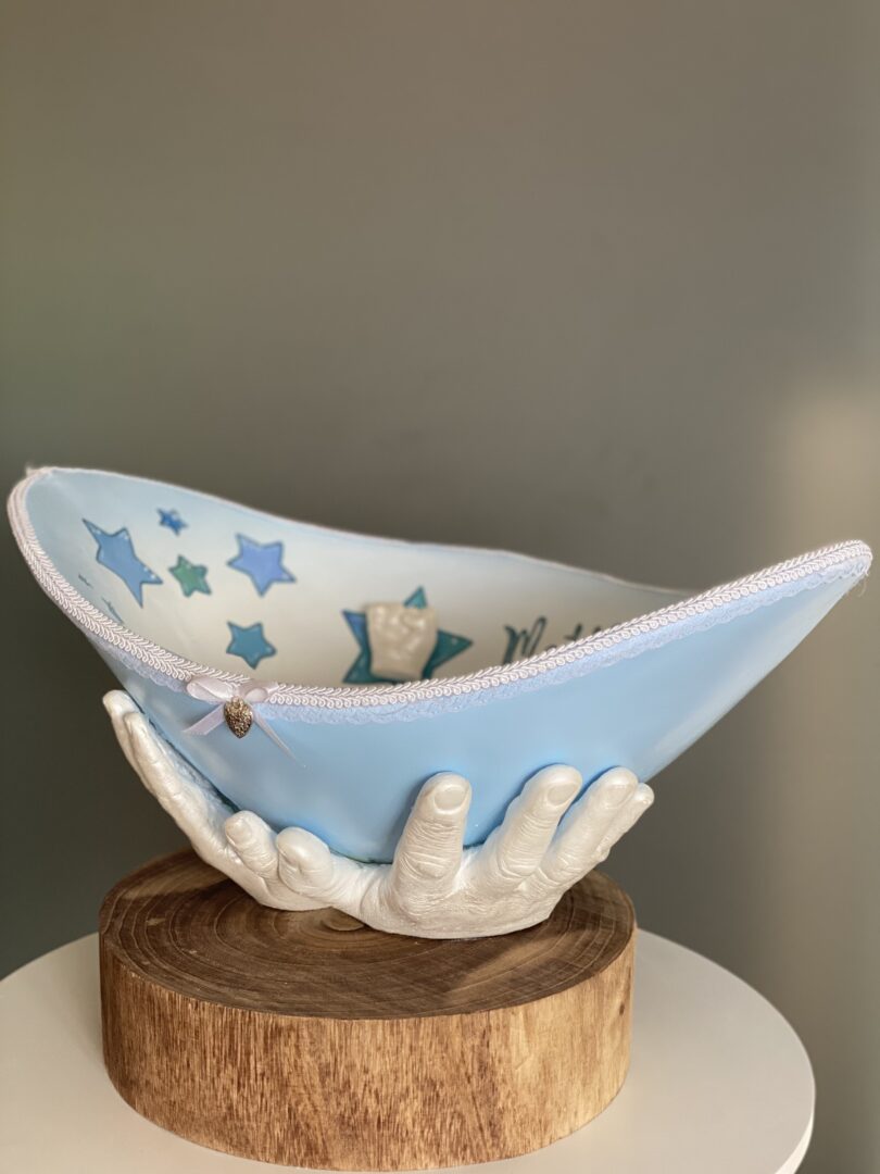 Belly Bowl als Babybauchschale, getragen von den Händen der Eltern auf einem natürlichen Holzsockel