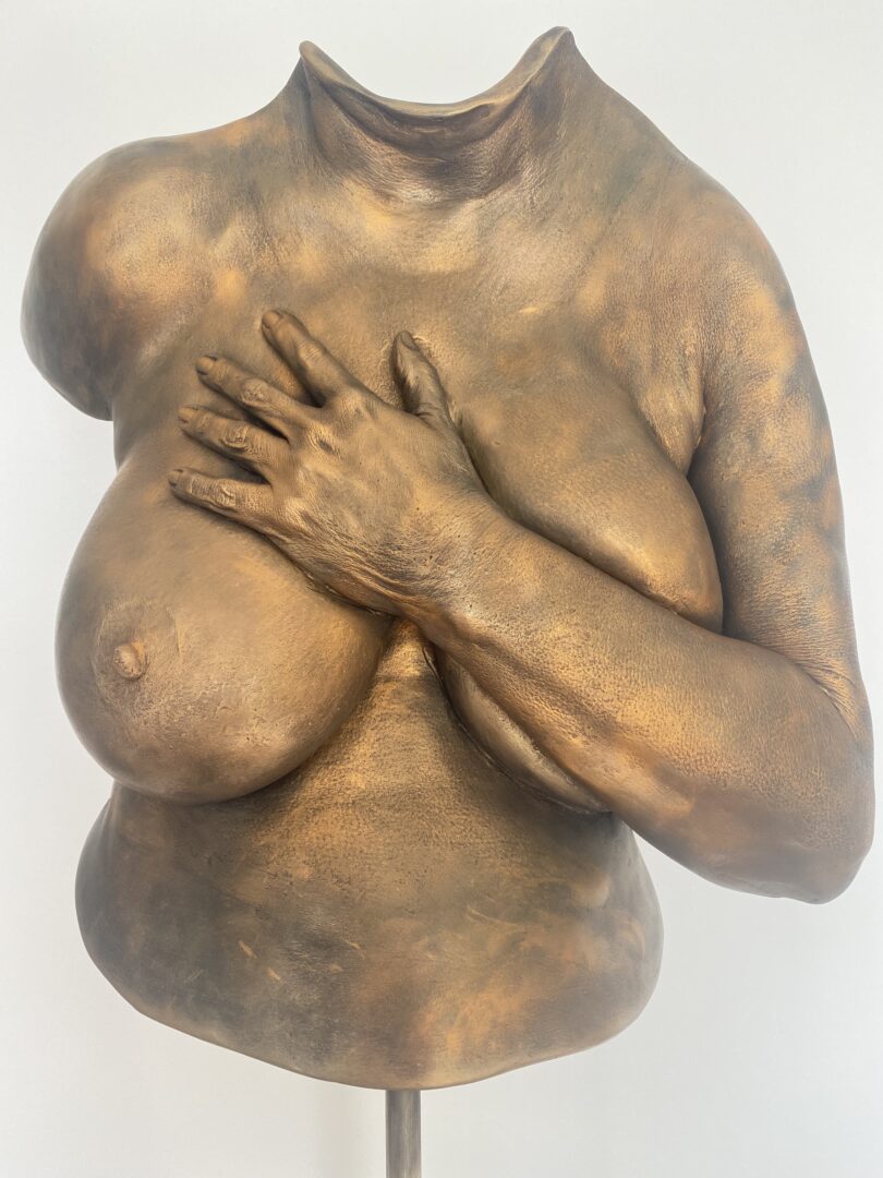 Bronzefarbener Oberkörperabdruck mit einem Arm und einer Hand auf dem Brustbein
