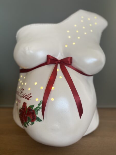 Weißer Babybauch-Gipsabdruck mit roten Rosen, Schleife und indirekter Beleuchtung