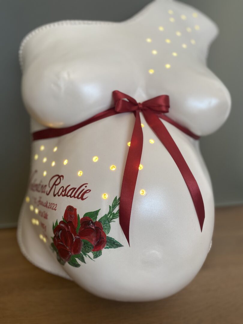Romantischer Babybauchabdruck mit Rosen und indirekter Beleuchtung