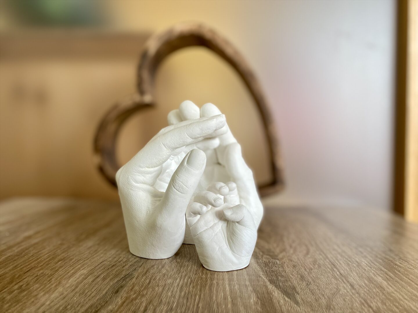 Gipsabdruck, bei dem Mama und Papa ihre Hände schützend über die kleine Hand ihres Babys legen
