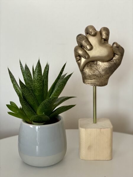 Detailgetreuer Gipsabdruck einer Kinderhand in Antikgold auf einem Holzsockel