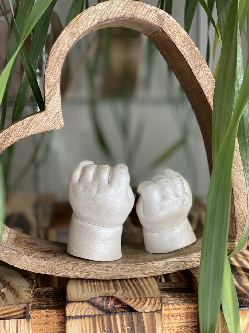 Babyhände als detailgetreuer Gipsabdruck in einer natürlichen Holzhalterung