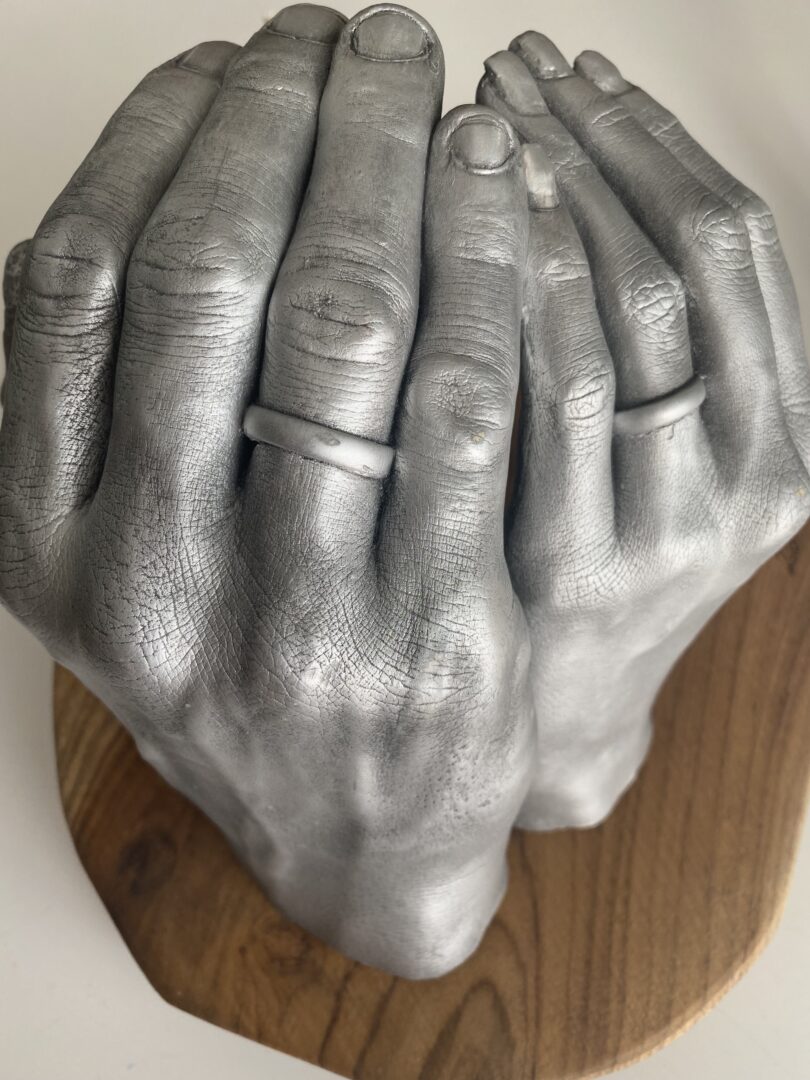 Paarhände als detailgetreuer Gipsabdruck zur Hochzeit, gemeinsam auf einem Holzsockel präsentiert