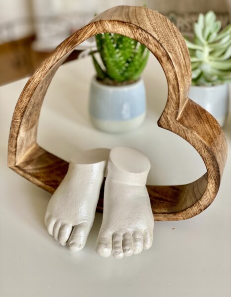 Babyfüße als detailgetreuer Gipsabdruck in einem Holzherz