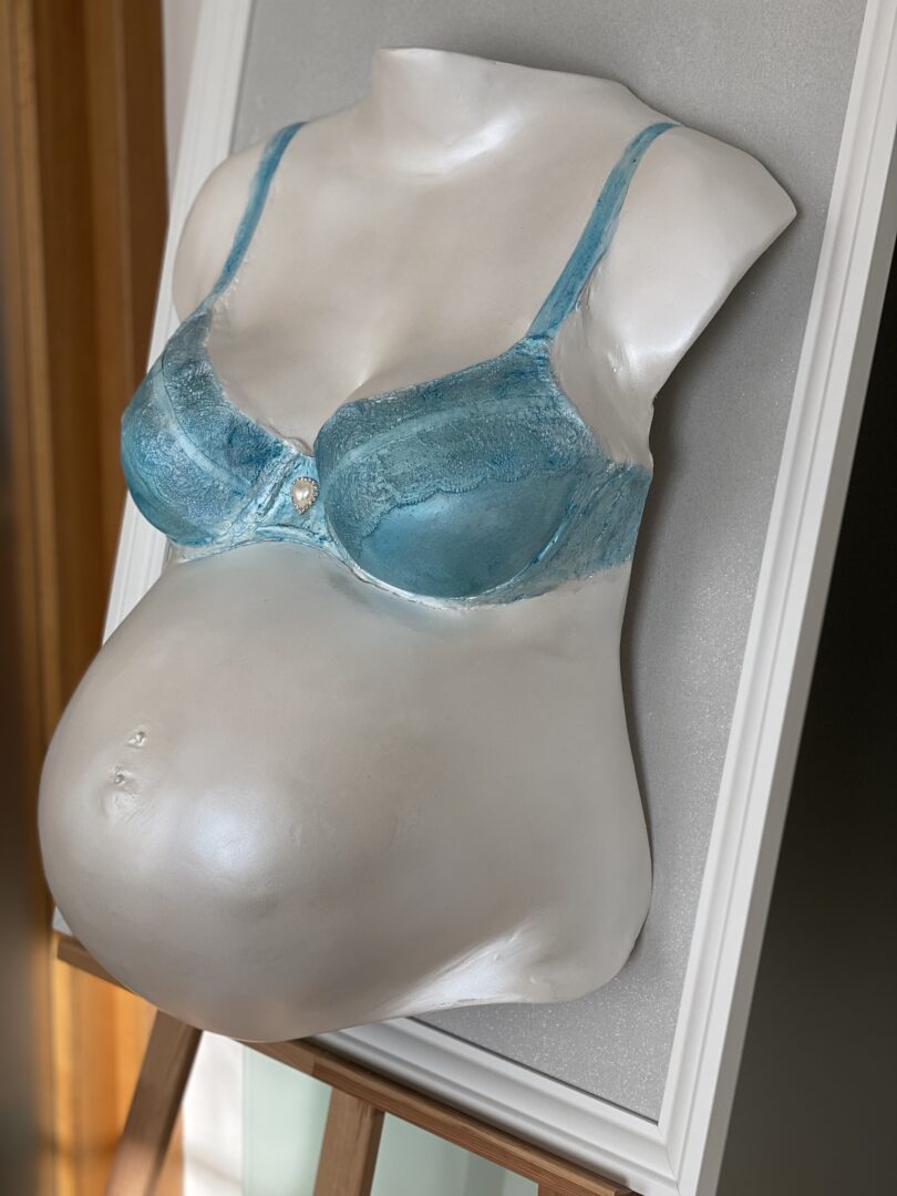 Originalgetreuer Babybauch Gipsabdruck mit transparenter blauer BH-Abformung im Rahmen